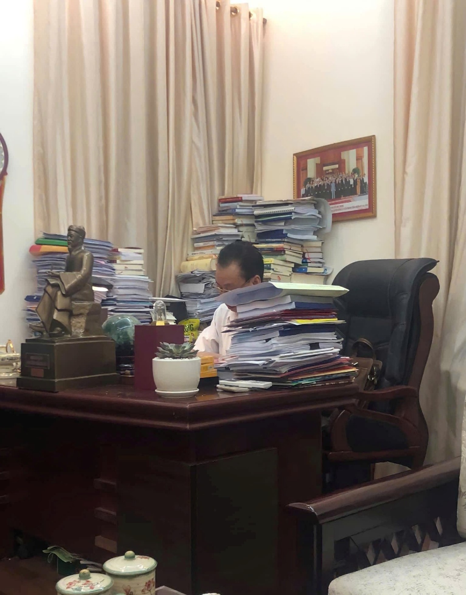 Ông Phùng Hữu Phú bên bàn làm việc tại nhà riêng, xung quanh là chồng tài liệu nghiên cứu – minh chứng cho một đời tận tụy với lý luận và tri thức.